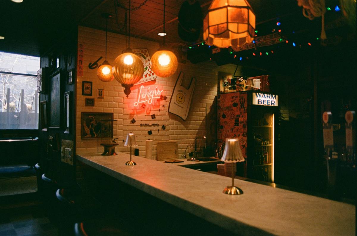 Before and after images of a home bar: harsh overhead lighting vs. layered warm ambient, task, and accent lighting