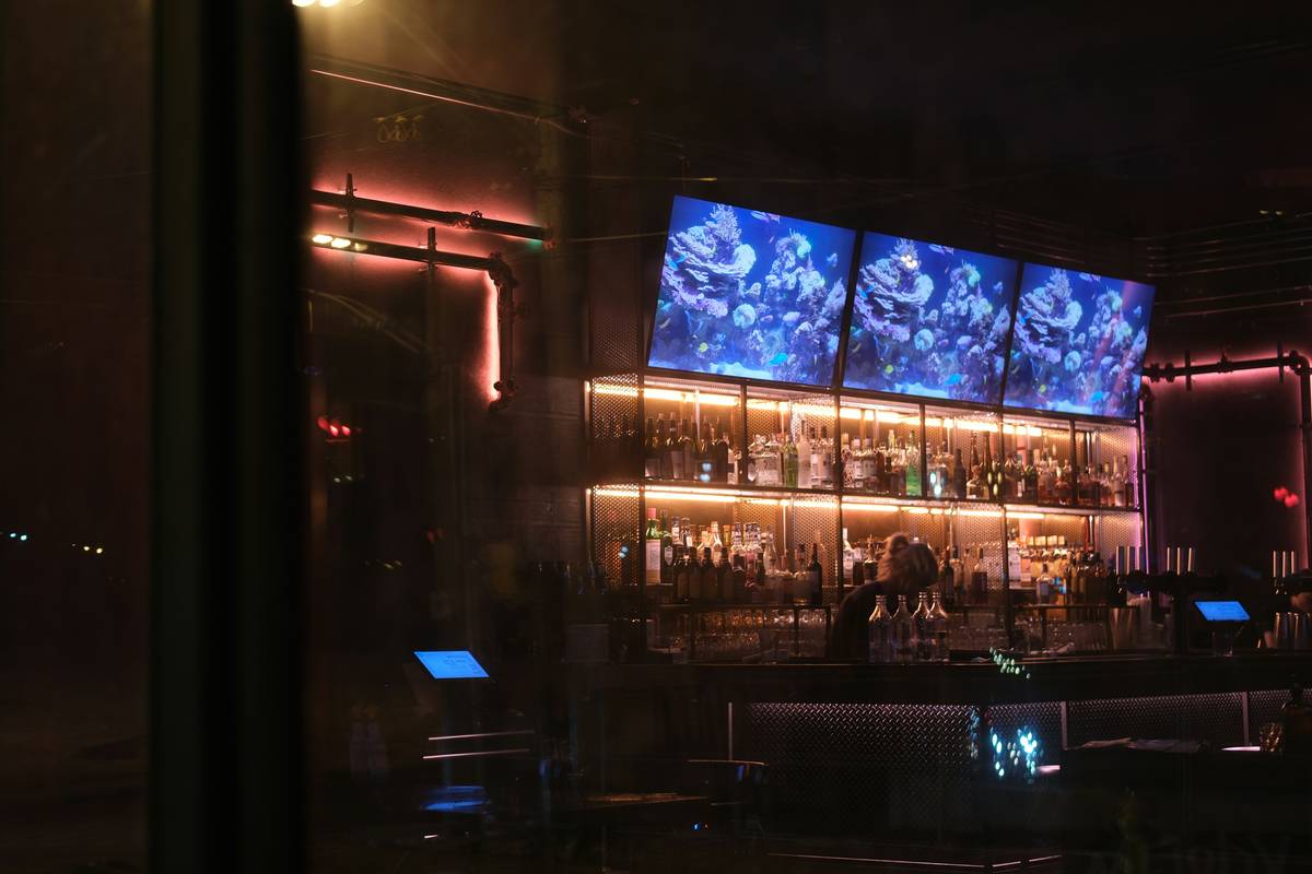 Diagram showing three layers of bar lighting: ambient ceiling lights, under-cabinet task lights, and LED strip accent lighting on back bar