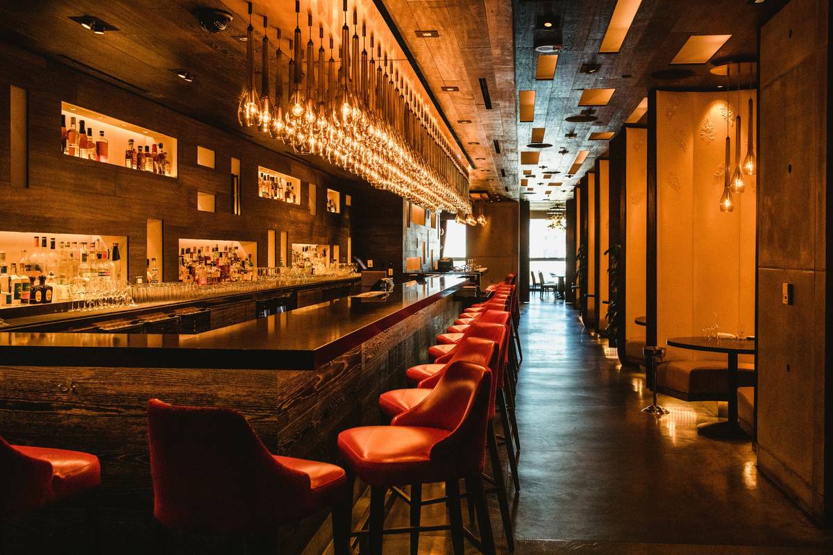Infographic showing ambient, task, and accent lighting layers in a home bar setup with recommended lux levels and color temps
