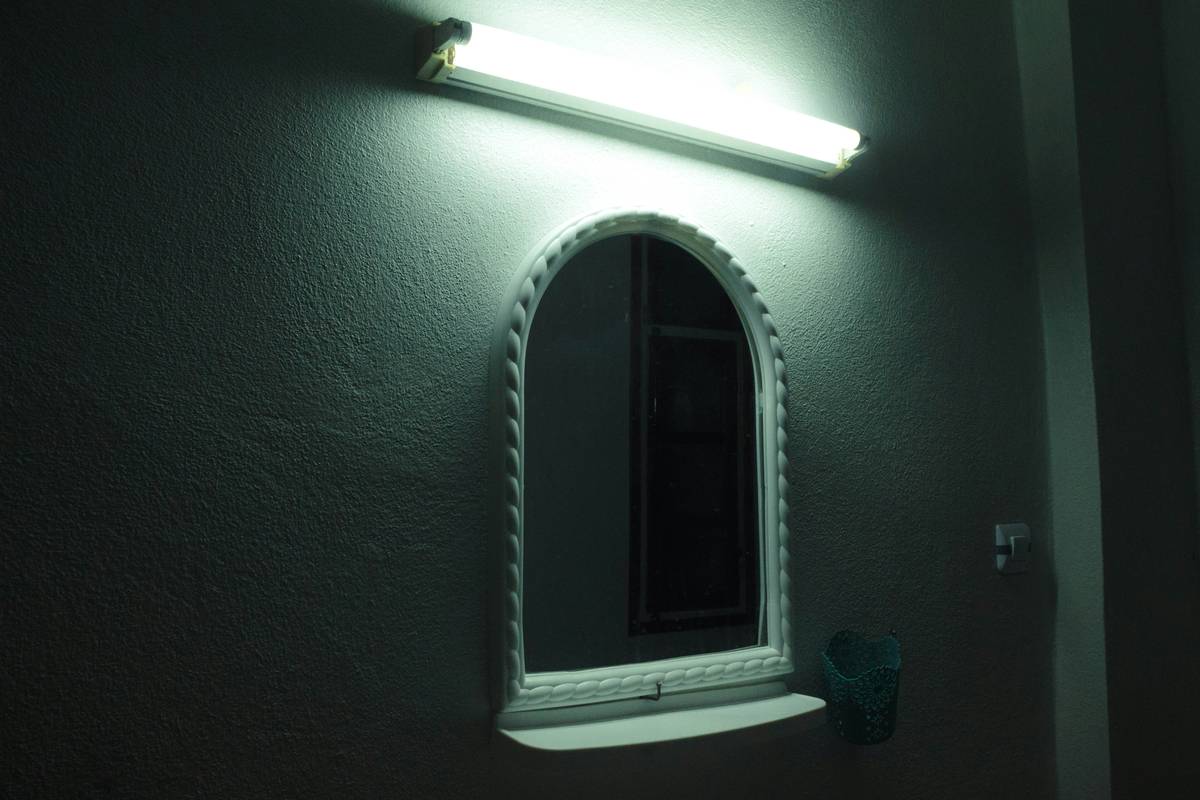 Side-by-side comparison: poor overhead bathroom lighting vs. proper bath bar lighting on mirror sides showing reduced shadows